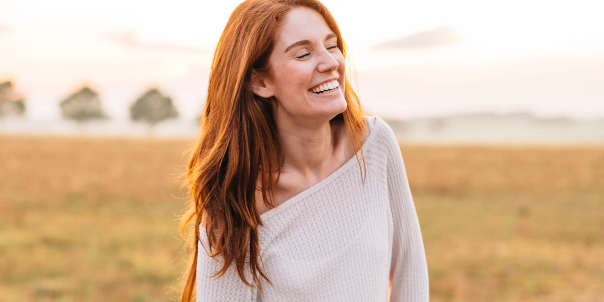 woman smiles while standing in grass field