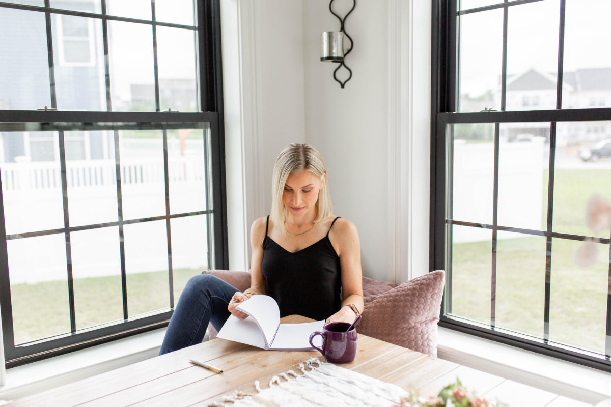 woman sitting at a table with a journal and a cup of coffee