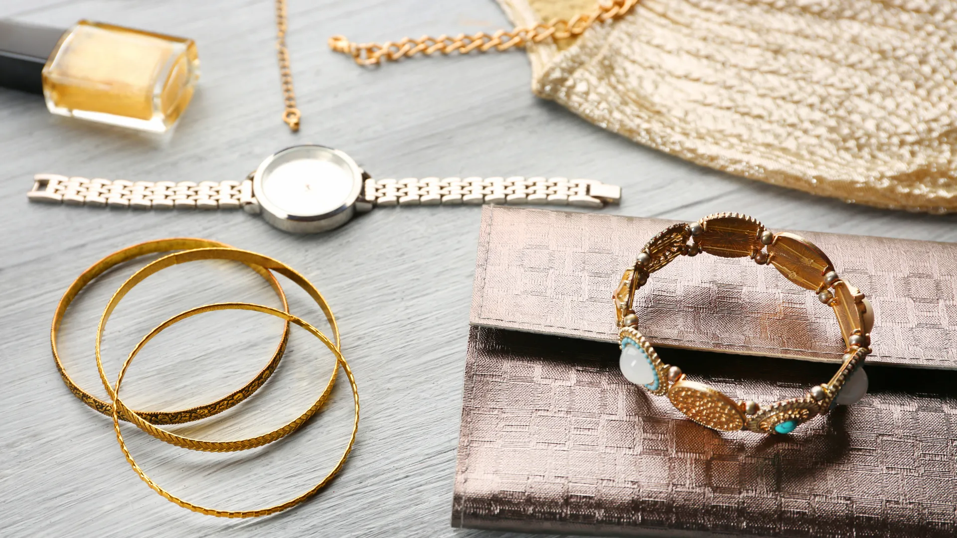 Accessories including a watch, bracelets, wallet, and necklace sitting on a table