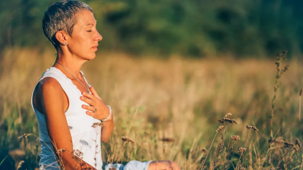 Woman sitting in a field learning to heal from a breakup