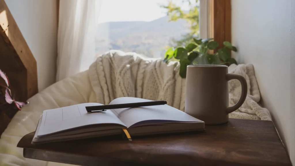 Journal sitting on a table with a potted plant and cable-knit blanket