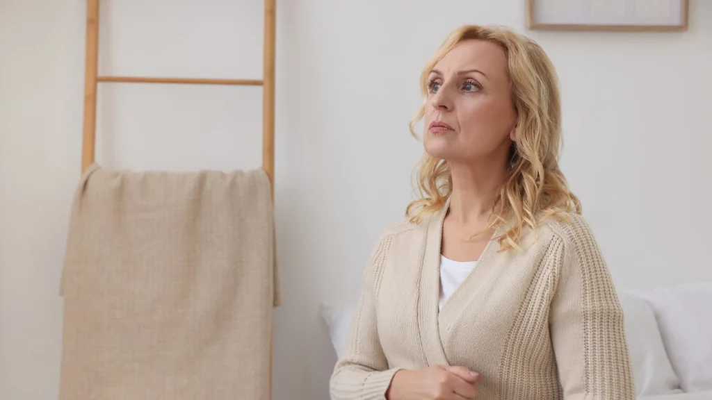 Woman with blonde hair wearing a cream sweater, sitting and taking time for herself after divorce