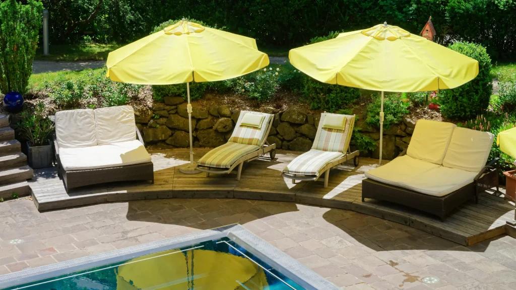 Yellow umbrellas set up over outdoor lounge chairs next to a swimming pool